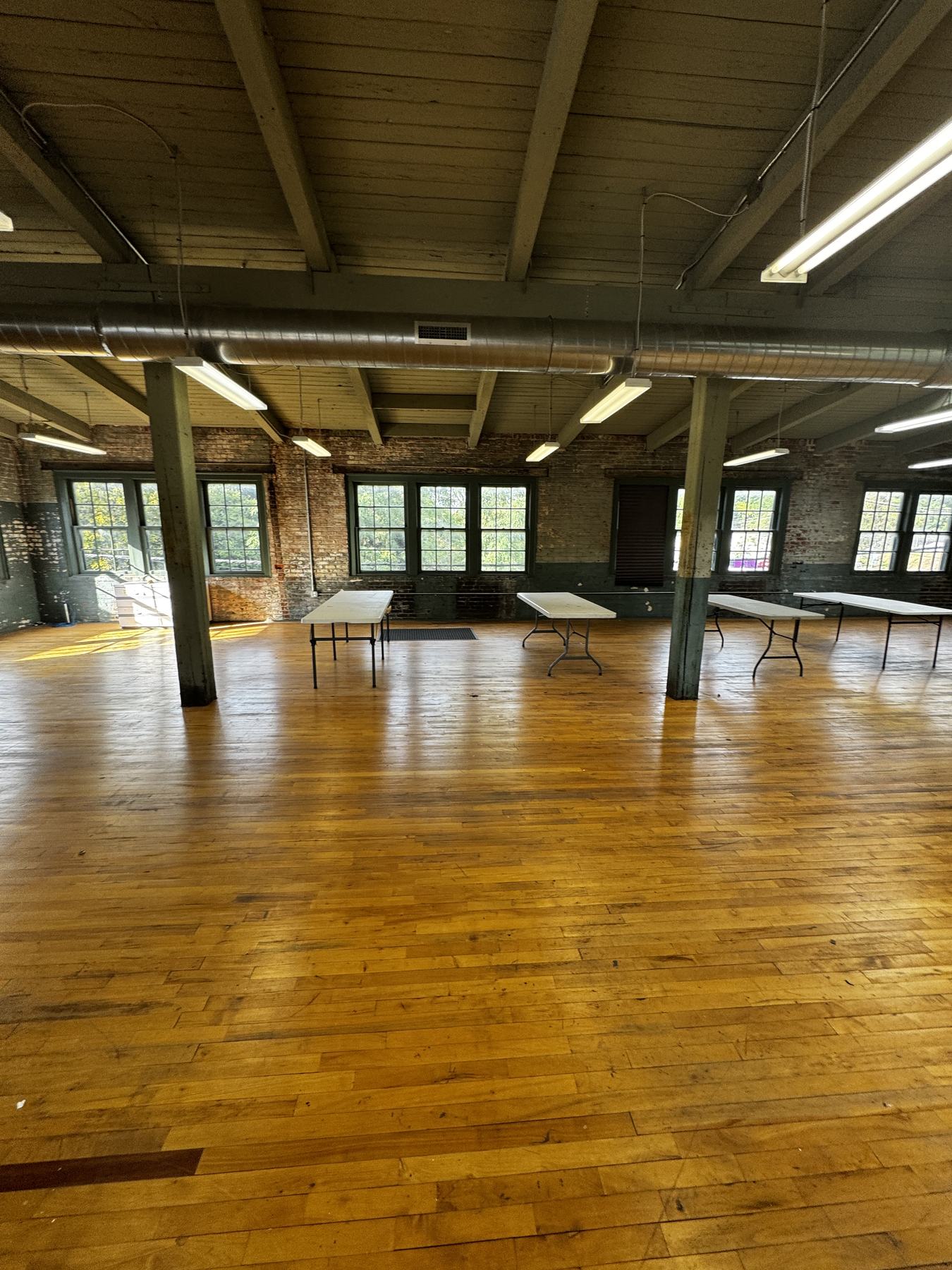 The Star View Room: an open wood plank floor running back to brick walls and tall windows, with painted timber posts and a beamed ceiling.
